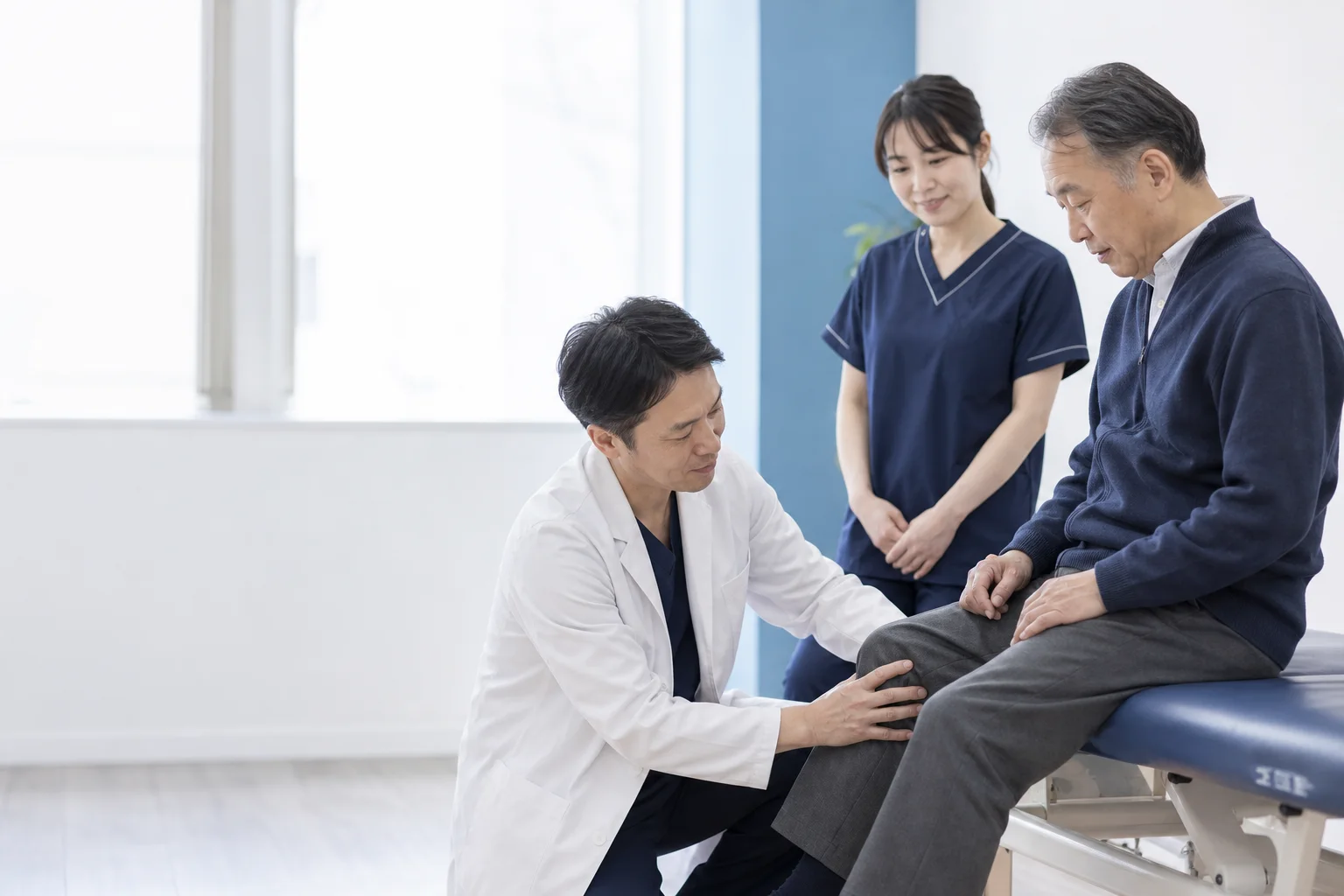 医師と理学療法士が患者さんの膝を診察する様子