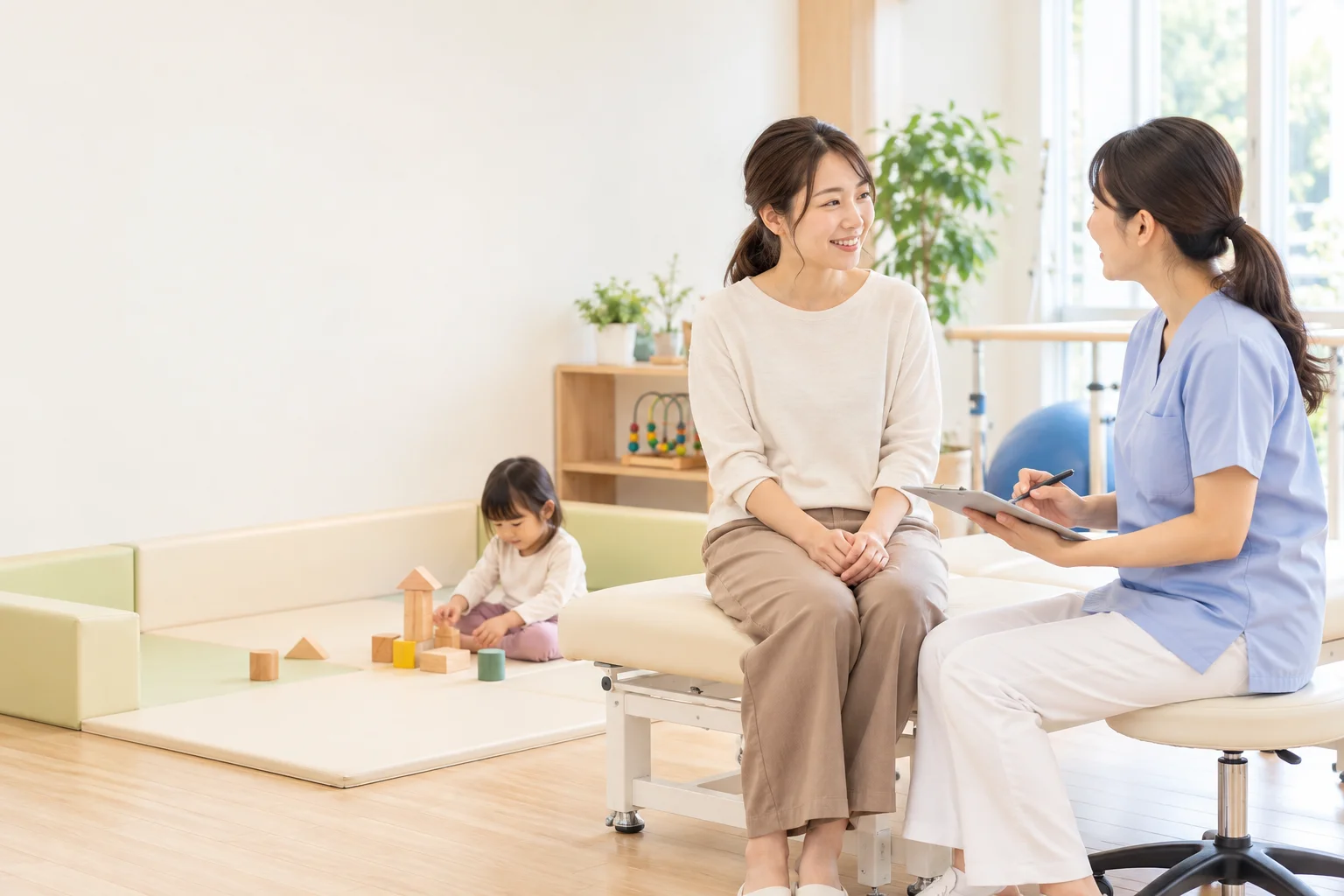 女性スタッフと話す女性と、近くで積み木で遊ぶ子ども