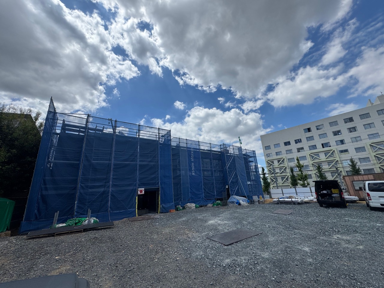 青い養生シートと足場に覆われた建築工事中のクリニック外観