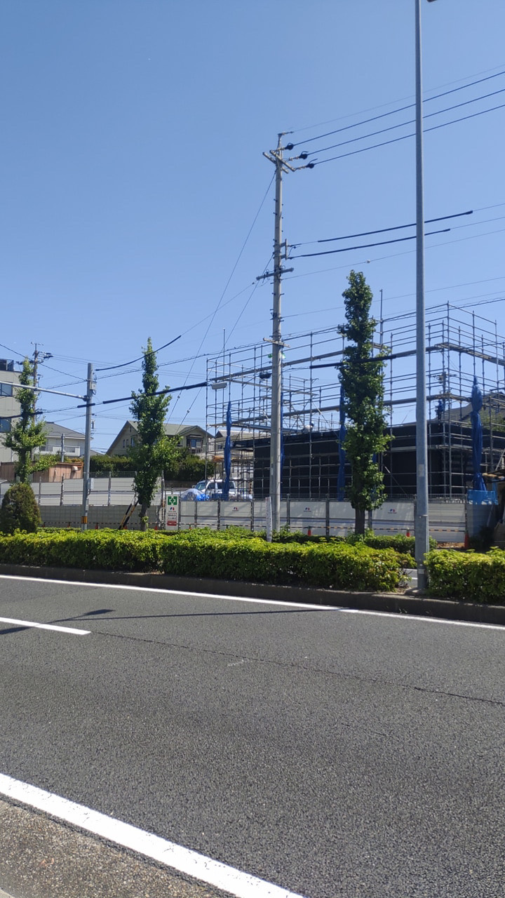 青空の下で鉄骨と足場の組み上げが進むクリニック建築現場