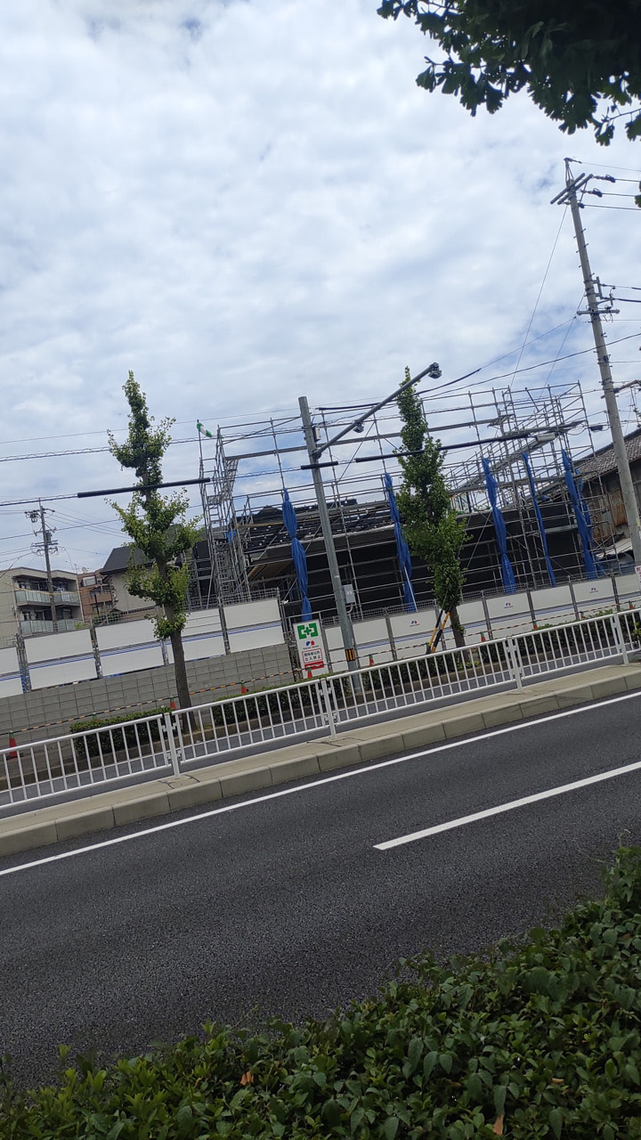 道路の向かい側から見た足場が組まれたクリニック建築現場